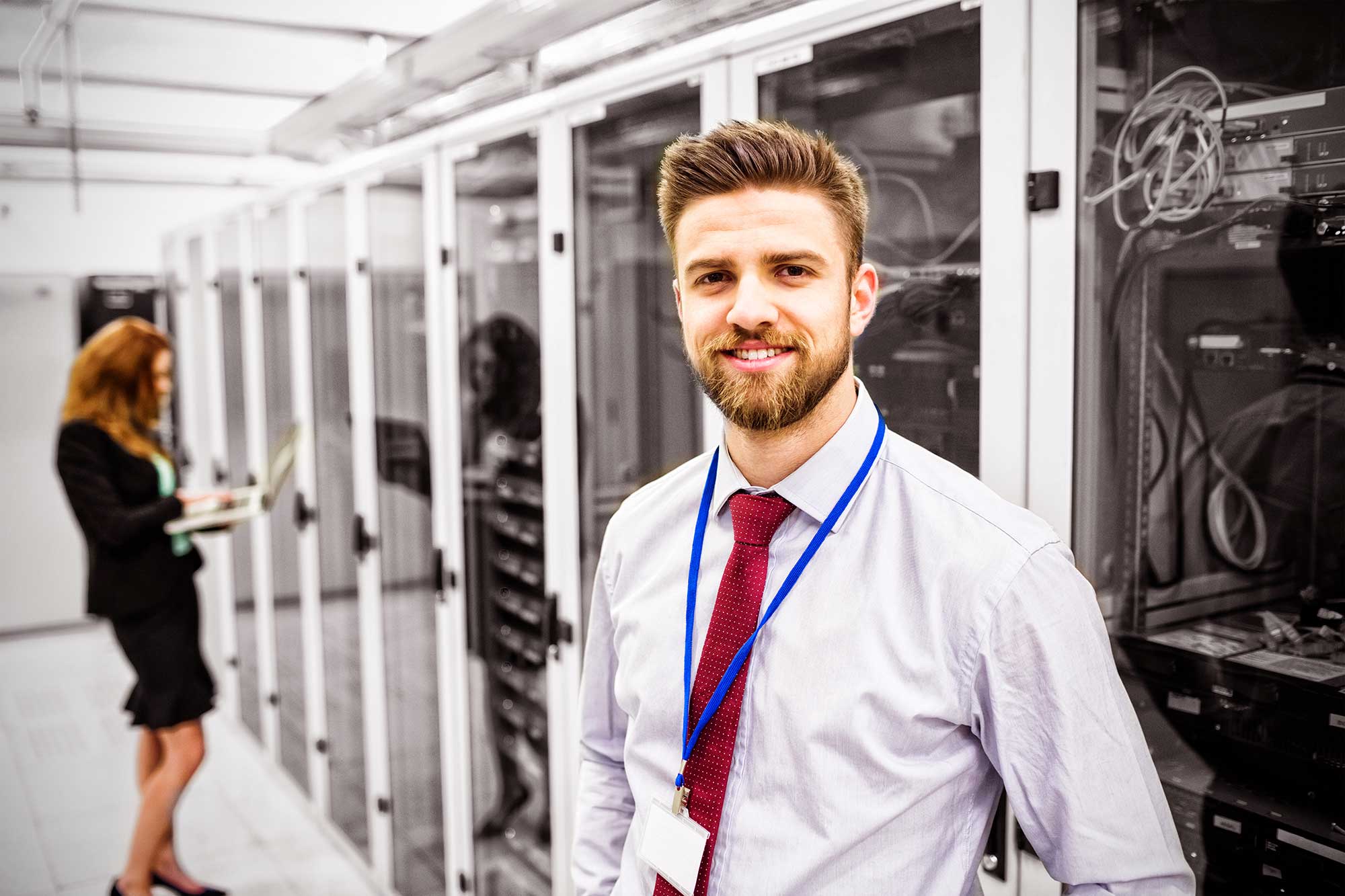 smiling-technician-standing-in-a-server-room-2021-08-30-06-01-14-utc